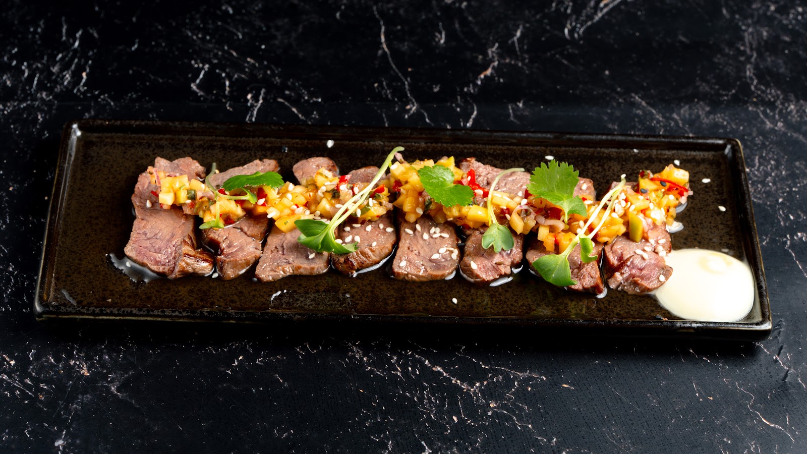 Beef-Tataki auf schwarzem Teller